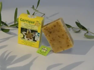 Savon Garrigue exfoliant doux de Natur'Aile, présenté avec son emballage jaune et le savon visible.